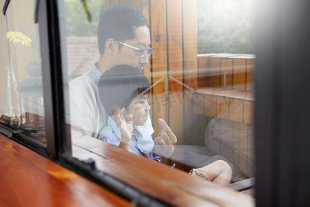 松鹤中国风名片摄影照片_中国父子俩在阳台上一起在阳光下吃早餐透过窗户拍摄