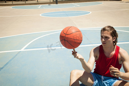 年轻男子篮球运动员在手指上旋转球