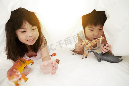 松鹤中国风名片摄影照片_年轻的中国男孩和女孩在床上玩床单下的玩具