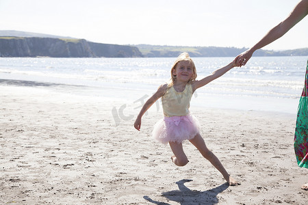 英国威尔士母亲和女儿穿着芭蕾舞裙在海滩上跑步