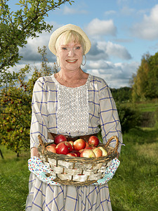 垂直农业摄影照片_成熟的女人提着一篮子苹果