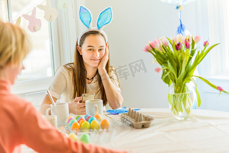 十几岁的女孩和哥哥在餐桌上为复活节染色煮熟的鸡蛋