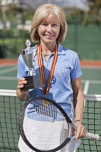 网球场上拿着奖杯的年长女性