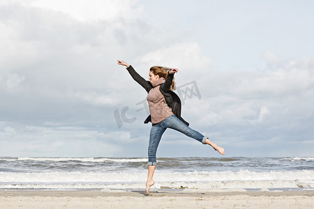 街舞教学摄影照片_海滩上跳跃的女人