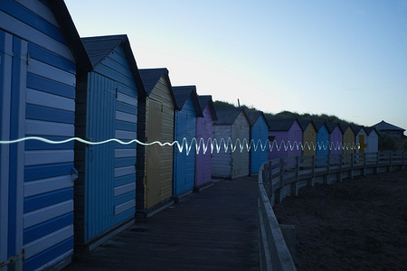 暮暮摄影照片_黄昏时分一排排五颜六色的海滩小屋小径明亮英国康沃尔布德