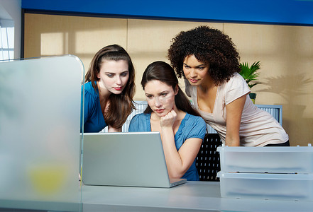 一群年轻女性在办公桌前拿着笔记本电脑