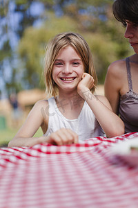 野餐桌摄影照片_在野餐桌上微笑的女孩