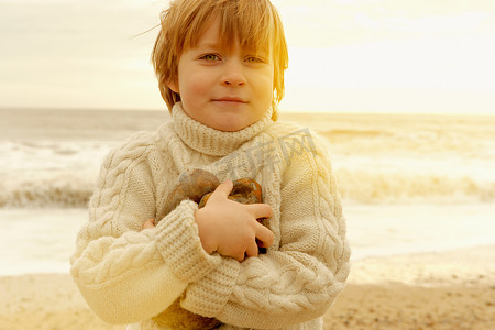 海滩上拿着石头的小男孩