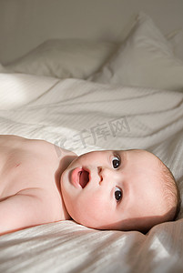 纯色床上用品摄影照片_躺在床上的男婴