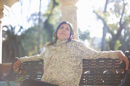 西班牙塞维利亚一名戴着耳机坐在板凳上看着别处的成熟女子