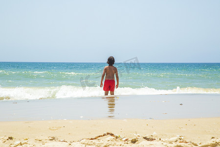 西班牙加的斯男孩在海里仰望地平线的背影