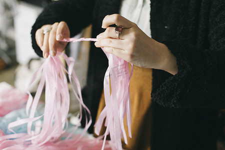 创意背景场摄影照片_女纺织设计师在设计工作室里旋转丝带的特写