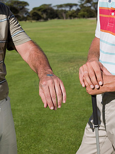 两个成熟男人一起打高尔夫球抛硬币