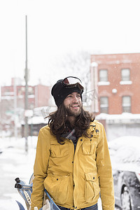成年了摄影照片_在积雪覆盖的街道上微笑的男性滑雪板运动员
