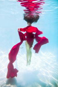 神秘摄影照片_一名女子穿着红色连衣裙披着红色布料漂浮在水下