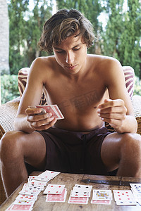 旅行打牌摄影照片_一名年轻男子在露台上打牌