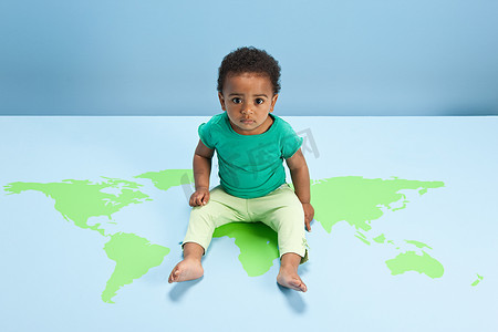 男婴坐在地板上的世界地图上