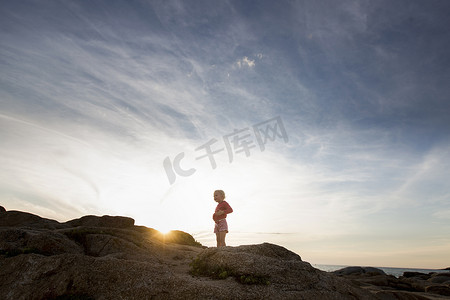 法国民族摄影照片_日落时分法国科西嘉岛卡尔维海岸岩石上的女孩子的剪影