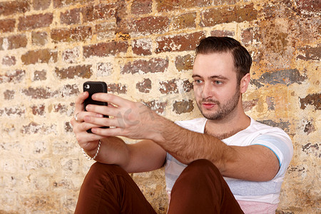 一名男子在砖墙上使用手机
