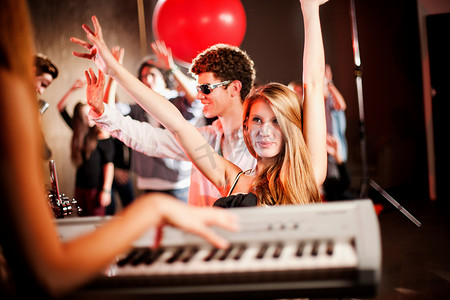 举起武器摄影照片_一名年轻女子与跳舞的人一起玩键盘