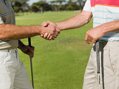 两个成熟的男人在高尔夫球场握手