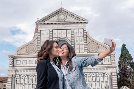 意大利托斯卡纳佛罗伦萨圣玛丽亚·诺维拉广场一对女同性恋在教堂前用智能手机自拍亲吻脸颊