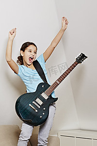 女孩弹着吉他张开嘴胜利地举起双臂