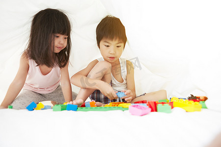 松鹤中国风名片摄影照片_年轻的中国男孩和女孩在床上玩床单下的玩具