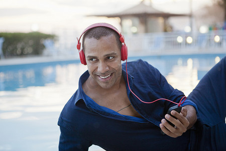 巴西里约热内卢一名中年男子在酒店泳池边听智能手机音乐