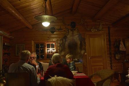 晚上三代家庭坐在小木屋的圣诞桌旁聊天
