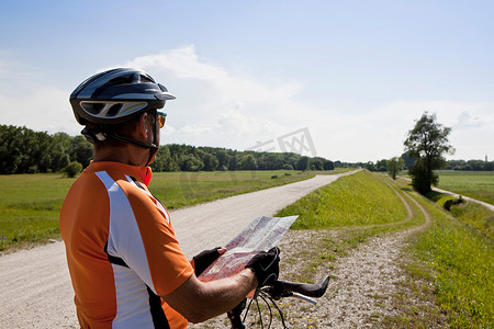 旅程地图摄影照片_骑自行车的人在乡村公路上阅读地图