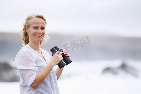 一名女子在海滩上用望远镜