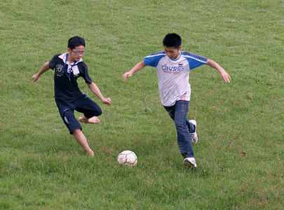 球场男生摄影照片_在操场草地上踢足球的男生人物高清图