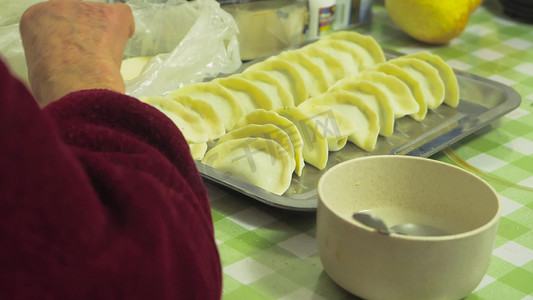 年味包饺子摄影照片_实拍新年氛围年味老人手工包饺子手部特写