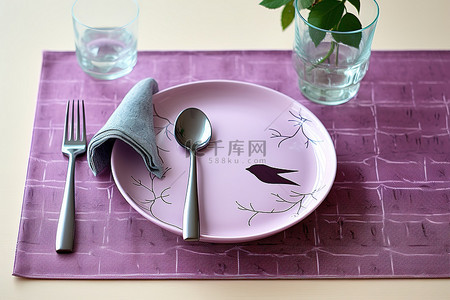 紫色的餐垫上放着一个紫色的小盘子和器皿