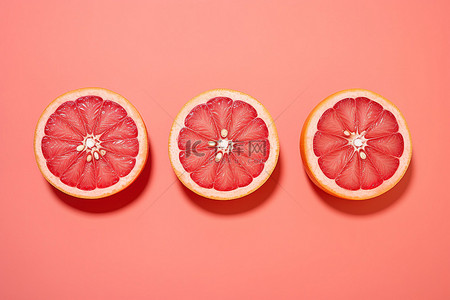 珊瑚橙背景图片_粉红色背景中的三个柚子脸