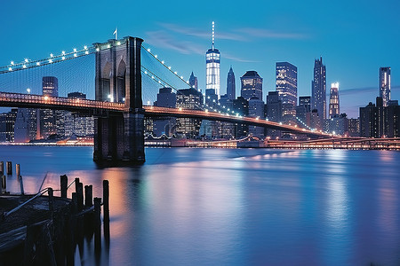美国大桥背景图片_当布鲁克林大桥在黄昏时分被点亮时，蓝色的灯光出现在水面上