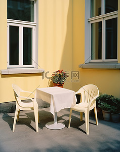 窗户旁边的庭院里有两张白色的椅子和桌子