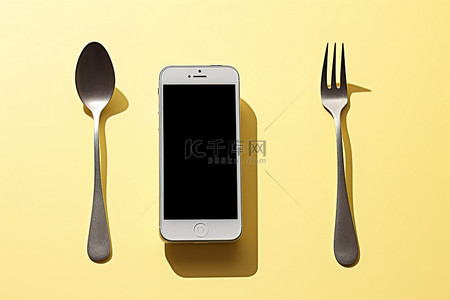 手机放背景图片_叉子和勺子旁边放着一部 iPhone