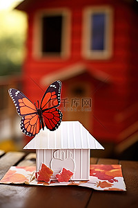 信封放在桌子上，上面有一只蝴蝶和红色的房子