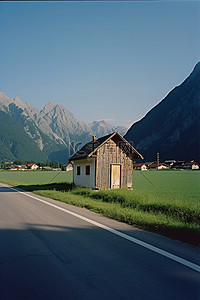 座背景图片_一条小路上的一座木屋的图像，后面有山