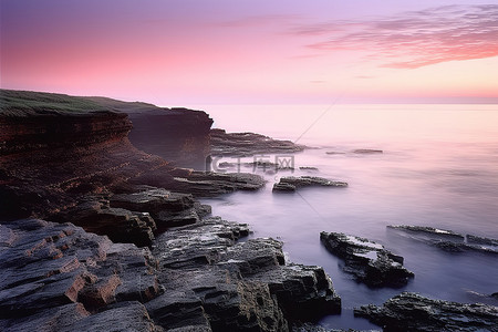 崎岖的海岸悬崖上美丽的粉红色和紫色日落
