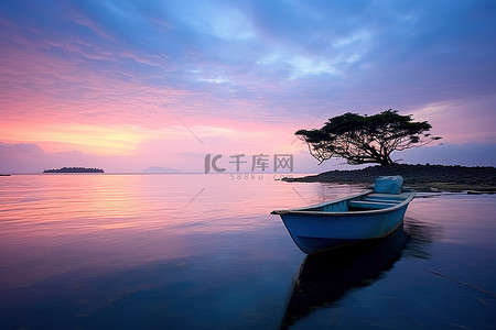 一艘小船坐落在水中的一座岛上，靠近美丽的粉红色日落