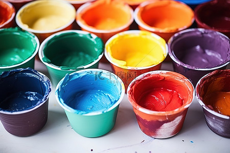 油画刷子背景图片_五颜六色的油漆碗里装满了各种颜色的混合油漆