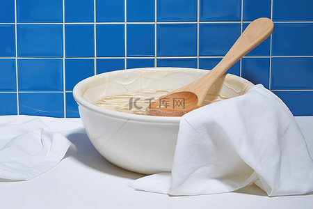蓝色瓷砖背景中的一碗洗涤液旁边放着一把木勺
