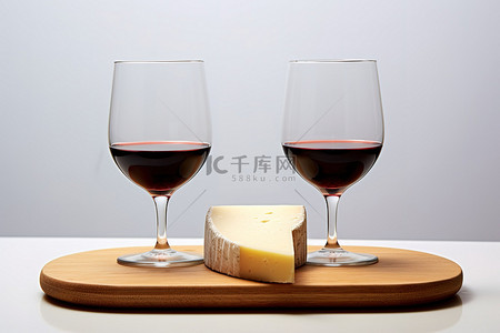 木板上的两个红酒杯和奶酪