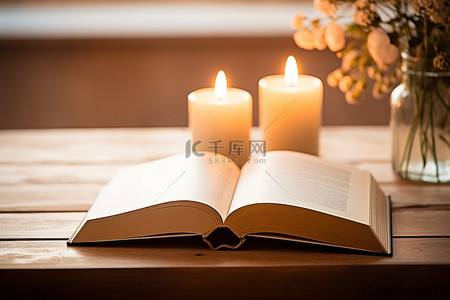 木桌上一本打开的书旁边坐着两根蜡烛