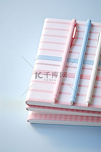 粉色笔记本，内含两支带条纹丝带的笔