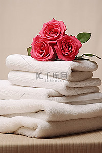 一叠毛巾，上面并排放着红玫瑰