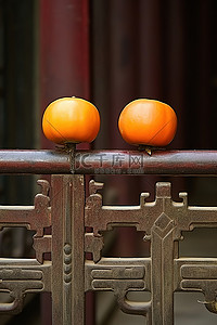 柿子椒熊背景图片_栅栏上坐着三个橙色水果